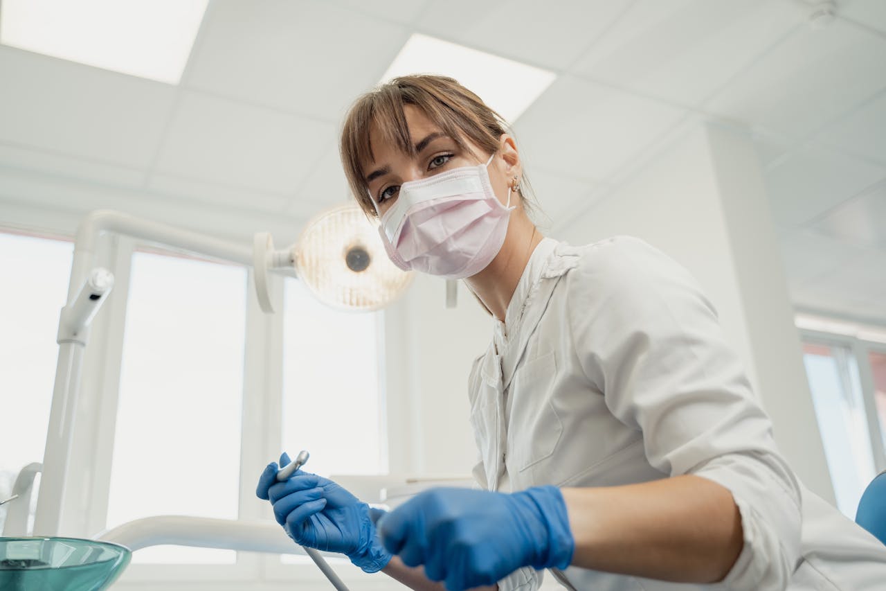 A female dentist in protective gear, focused and ready for a dental procedure in a modern clinic.
